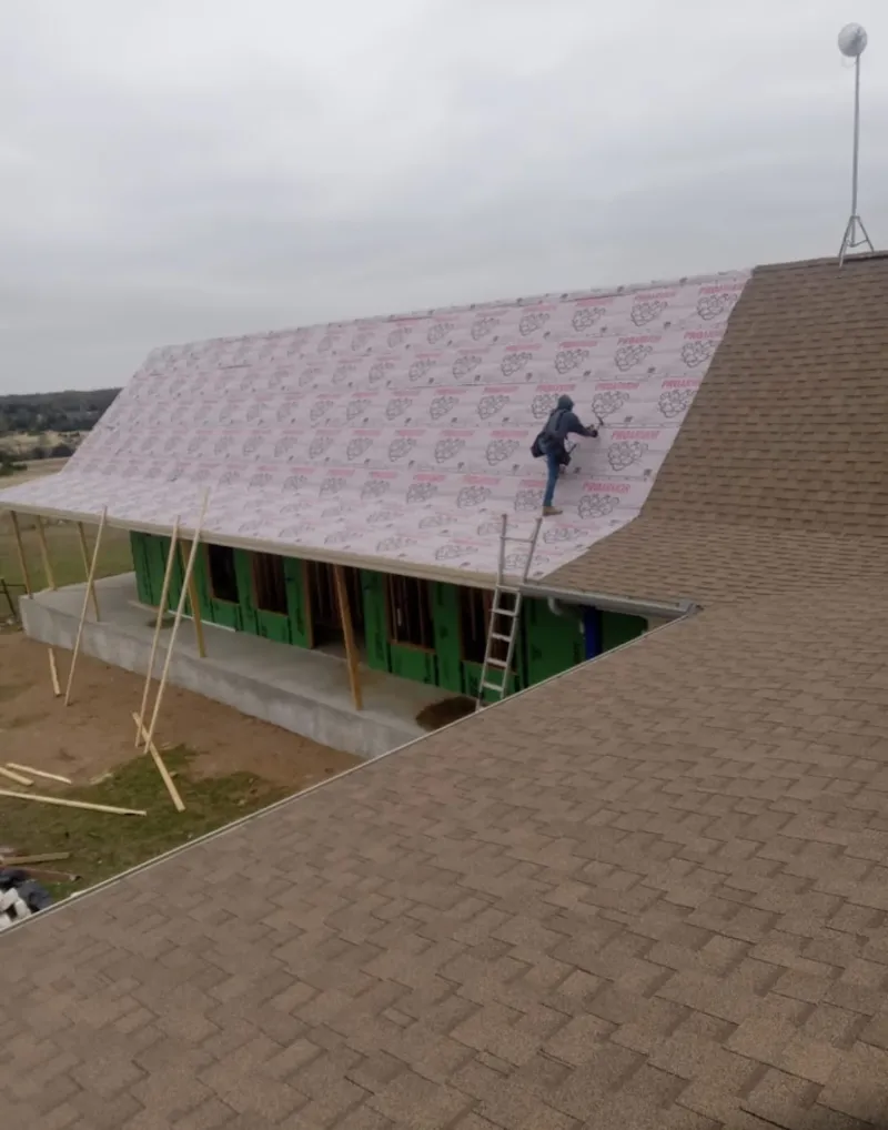 Worker preparing underlayment for a metal roof installation in Odessa